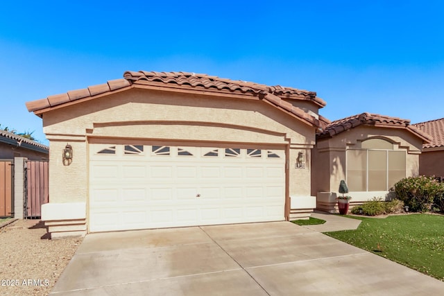 mediterranean / spanish-style home with a tile roof, a garage, driveway, and stucco siding