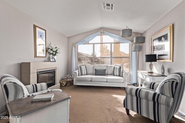 living room featuring visible vents, lofted ceiling, carpet, and a glass covered fireplace