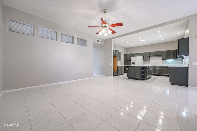 kitchen featuring gray cabinetry, a kitchen island, ceiling fan, white fridge with ice dispenser, and sink