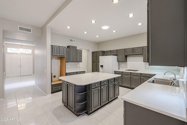 kitchen featuring light tile patterned floors, sink, a kitchen island, gas cooktop, and white fridge with ice dispenser