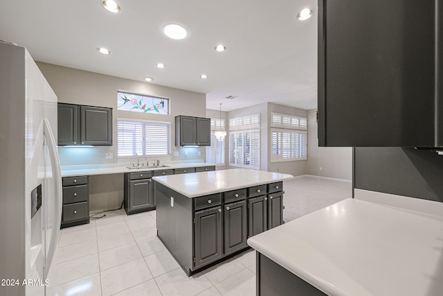 kitchen featuring light tile patterned floors, a center island, white refrigerator with ice dispenser, and sink