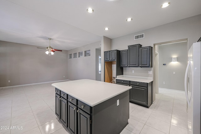 kitchen featuring ceiling fan, light tile patterned flooring, a kitchen island, gray cabinets, and white fridge