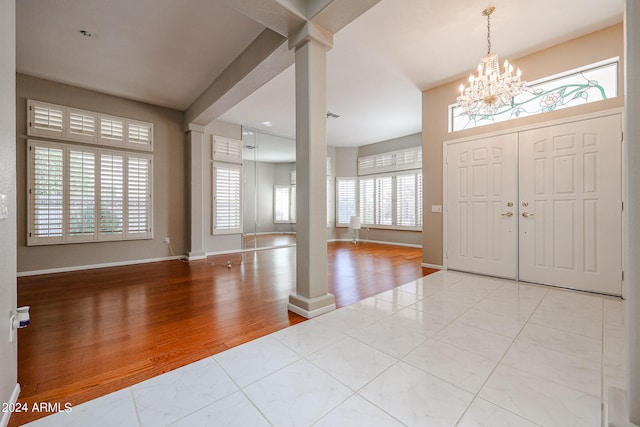 entryway with light wood-type flooring, decorative columns, and a wealth of natural light