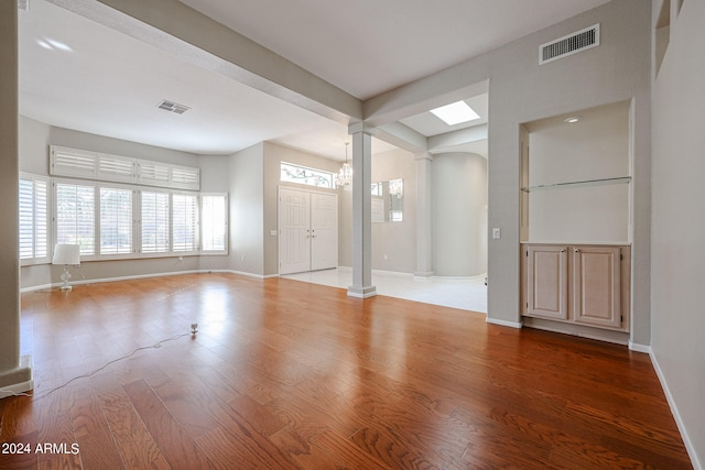 empty room featuring decorative columns and hardwood / wood-style floors