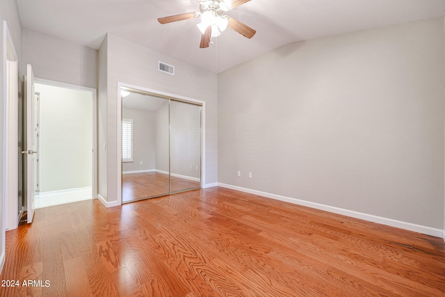 unfurnished bedroom featuring light wood-type flooring, vaulted ceiling, ceiling fan, and a closet