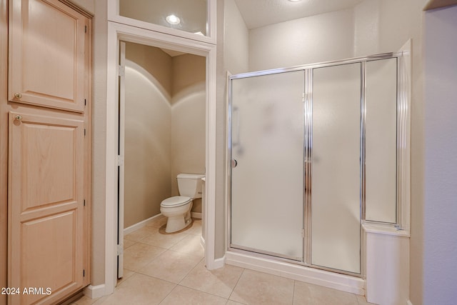 bathroom with tile patterned flooring, a shower with shower door, and toilet