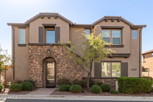 mediterranean / spanish home featuring a tile roof, stone siding, and stucco siding