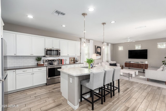 kitchen featuring visible vents, tasteful backsplash, open floor plan, stainless steel appliances, and wood tiled floor