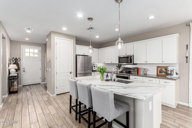 kitchen with tasteful backsplash, visible vents, appliances with stainless steel finishes, and light wood-type flooring