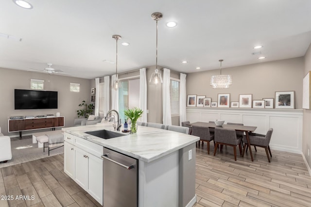 kitchen featuring stainless steel dishwasher, wood tiled floor, open floor plan, and a sink