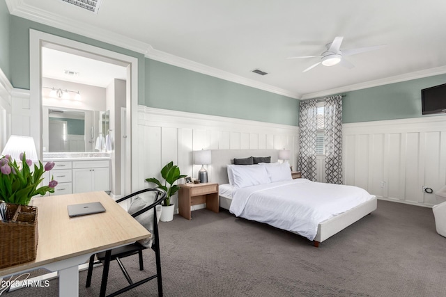 carpeted bedroom with visible vents, ensuite bath, ornamental molding, and wainscoting