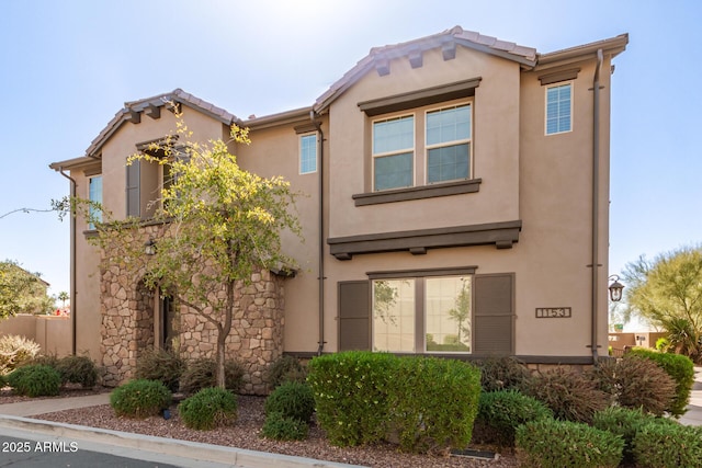 view of front of property with stucco siding, stone siding, and a tiled roof