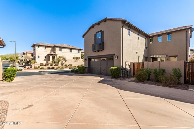 view of property exterior featuring stucco siding, a garage, driveway, and fence