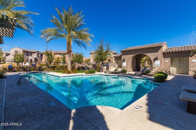 pool with a patio area, a residential view, and fence