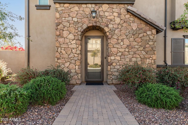 property entrance with stucco siding and stone siding