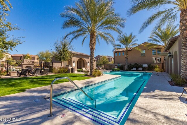 pool with a patio area, an outdoor fireplace, and fence