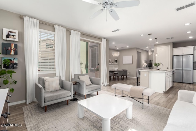 living area featuring recessed lighting, visible vents, baseboards, and light wood-style floors