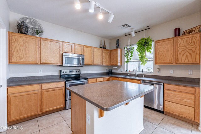 kitchen featuring stainless steel appliances, sink, a center island, light tile patterned floors, and track lighting