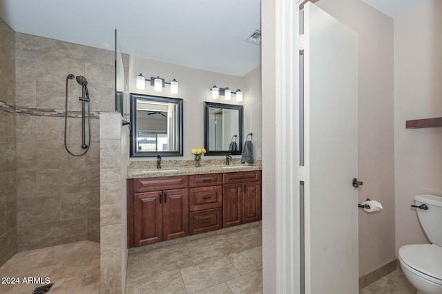 bathroom with tile patterned floors, vanity, toilet, and tiled shower