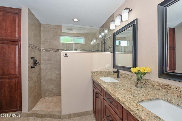 bathroom with tile patterned floors, vanity, and tiled shower