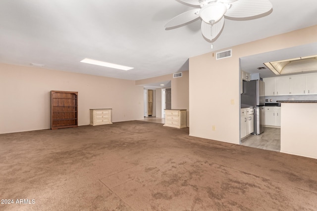 unfurnished living room featuring ceiling fan and light colored carpet