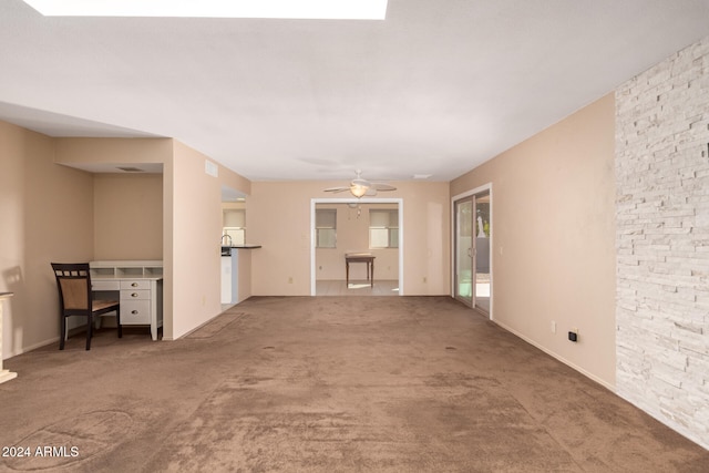 unfurnished living room with ceiling fan and carpet