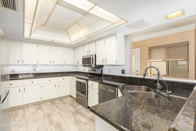 kitchen featuring sink, white cabinetry, appliances with stainless steel finishes, and dark stone counters