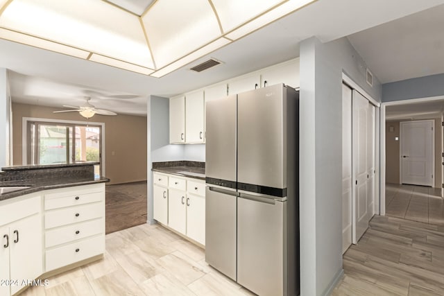 kitchen featuring ceiling fan, white cabinets, light carpet, and stainless steel refrigerator