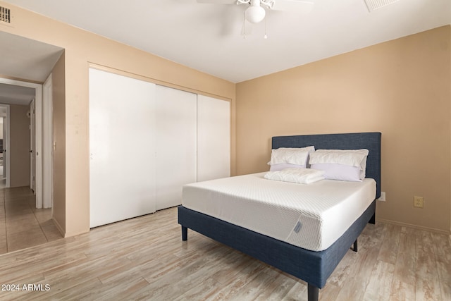 bedroom with light wood-type flooring, ceiling fan, and a closet