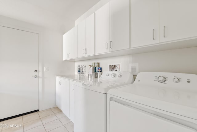 laundry room featuring cabinets, independent washer and dryer, and light tile patterned floors