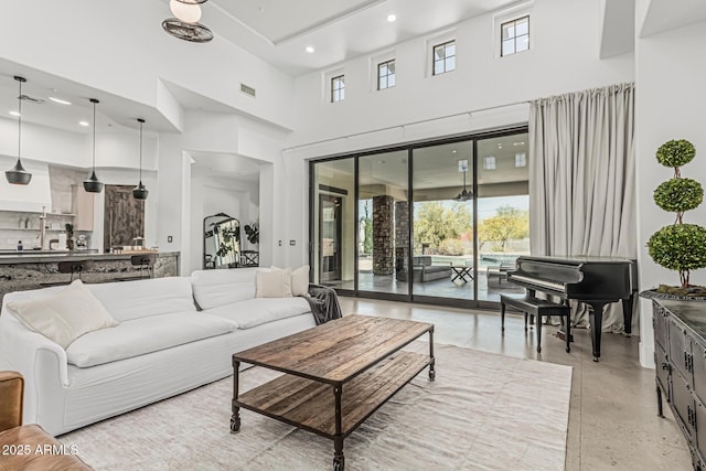 living area with a high ceiling, recessed lighting, and visible vents