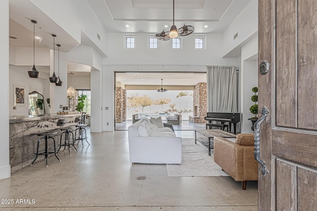 living area featuring recessed lighting, a tray ceiling, an inviting chandelier, and a towering ceiling