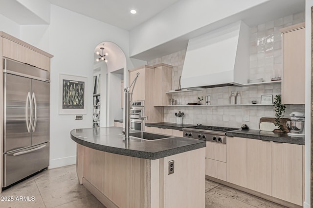kitchen featuring dark countertops, light brown cabinets, decorative backsplash, and stainless steel appliances
