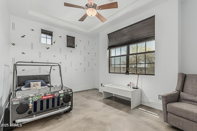 bedroom with baseboards, a ceiling fan, a raised ceiling, and concrete flooring