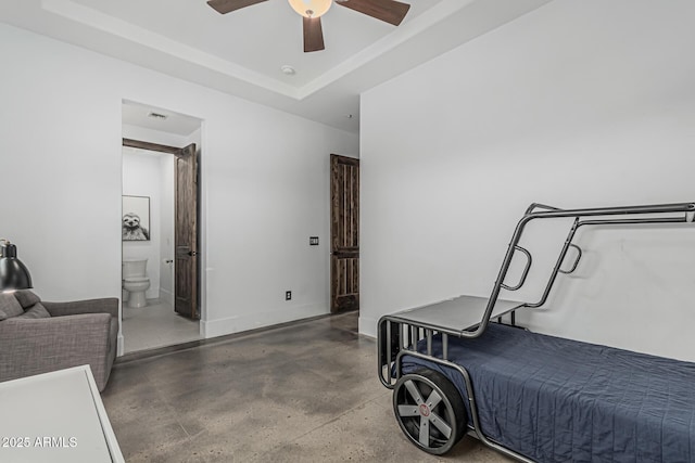 bedroom with visible vents, concrete flooring, ensuite bathroom, ceiling fan, and a tray ceiling