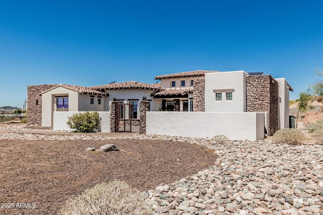 view of front of house featuring a fenced front yard, stucco siding, a tiled roof, and stone siding