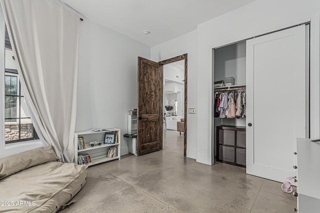 bedroom featuring a closet and finished concrete flooring
