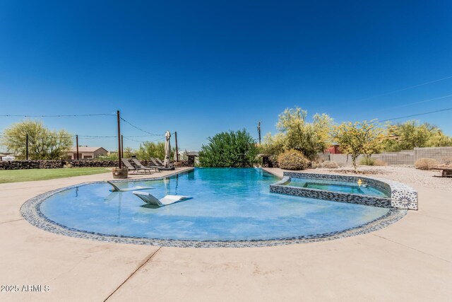 view of pool with a patio area, fence, and a pool with connected hot tub