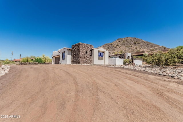 view of front of property featuring a garage, driveway, a mountain view, and stucco siding