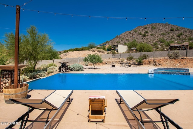 view of pool with a pool with connected hot tub, a mountain view, a fenced backyard, and a patio area