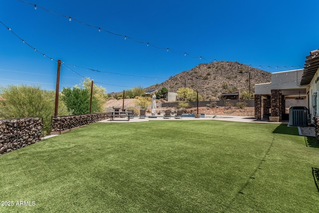 view of yard with a patio, central AC unit, a mountain view, and fence