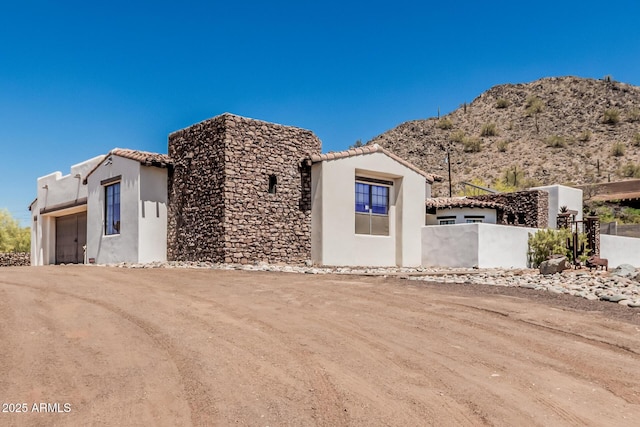 view of front of house with an attached garage, stucco siding, a tiled roof, and fence