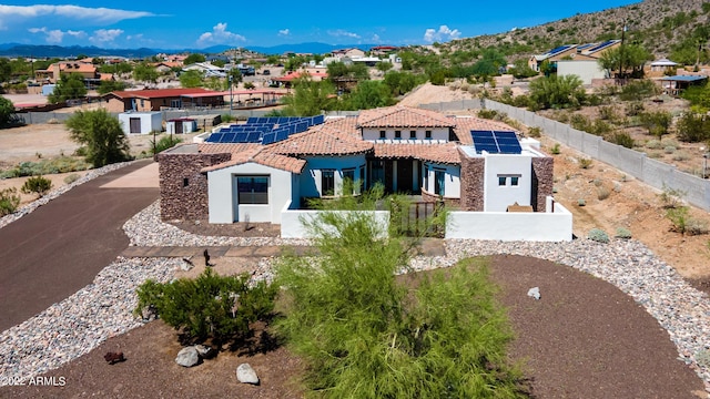 mediterranean / spanish-style home featuring a mountain view, solar panels, fence private yard, and stucco siding