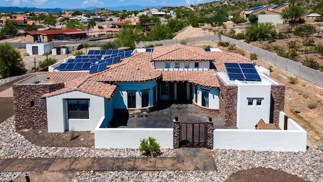 mediterranean / spanish-style home featuring a fenced backyard, roof mounted solar panels, stucco siding, and a mountain view