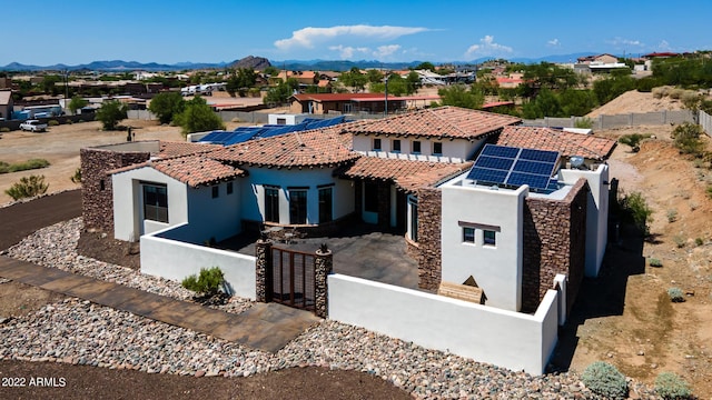 mediterranean / spanish-style home with a fenced front yard, stucco siding, a residential view, and solar panels