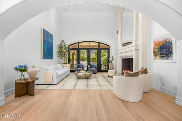 living room with a high ceiling, light hardwood / wood-style flooring, and french doors