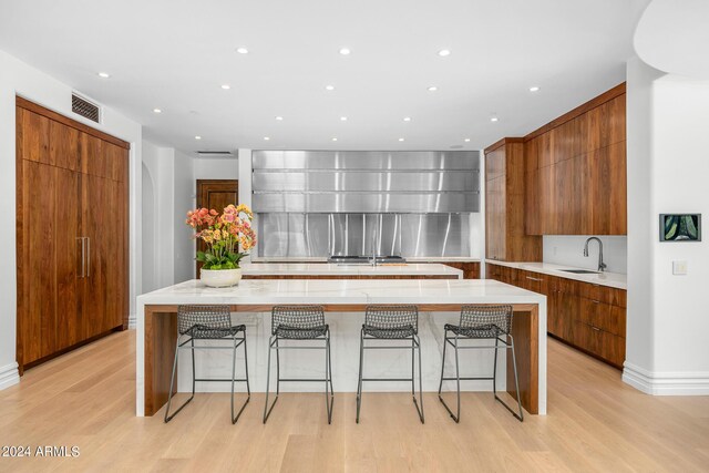 kitchen featuring a kitchen breakfast bar, light hardwood / wood-style floors, sink, and a spacious island