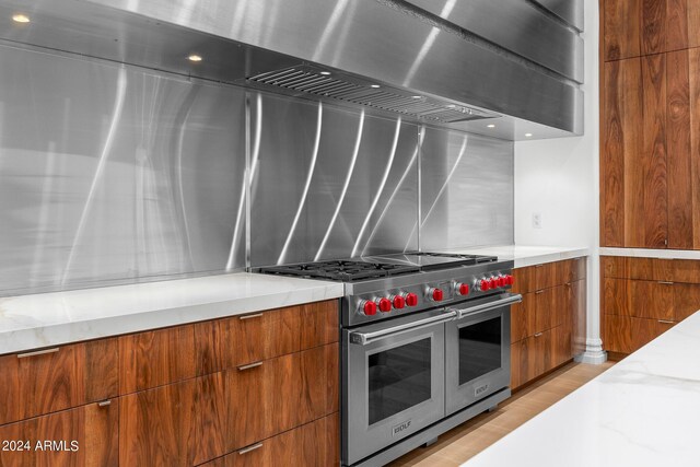 kitchen with light stone countertops, light hardwood / wood-style floors, and double oven range