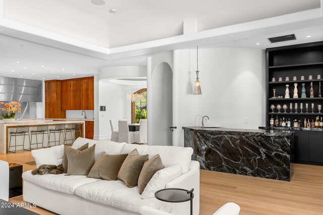 living room featuring wet bar and light hardwood / wood-style flooring