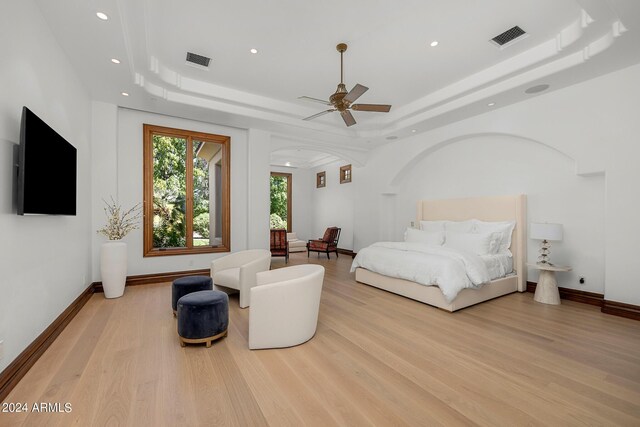 bedroom featuring ceiling fan, light wood-type flooring, and a raised ceiling